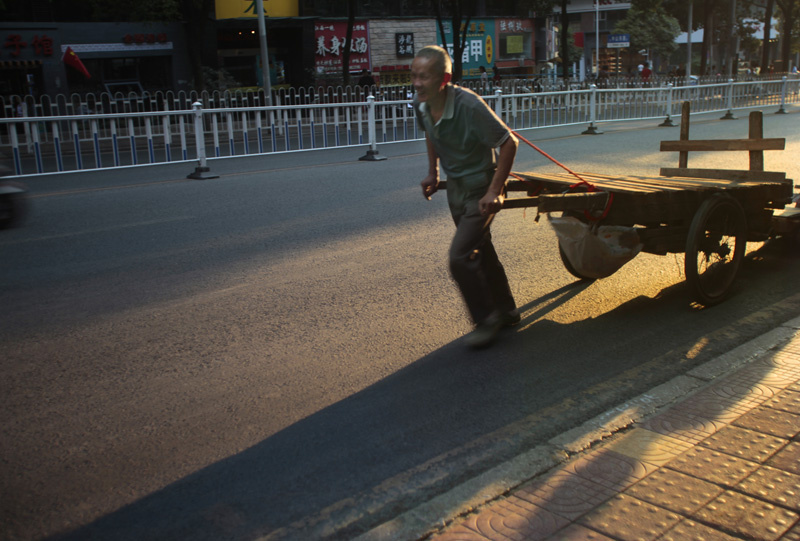 干了一天苦力活,心满意足,拉着板车回家的男人满脸笑容地行走在贵阳市