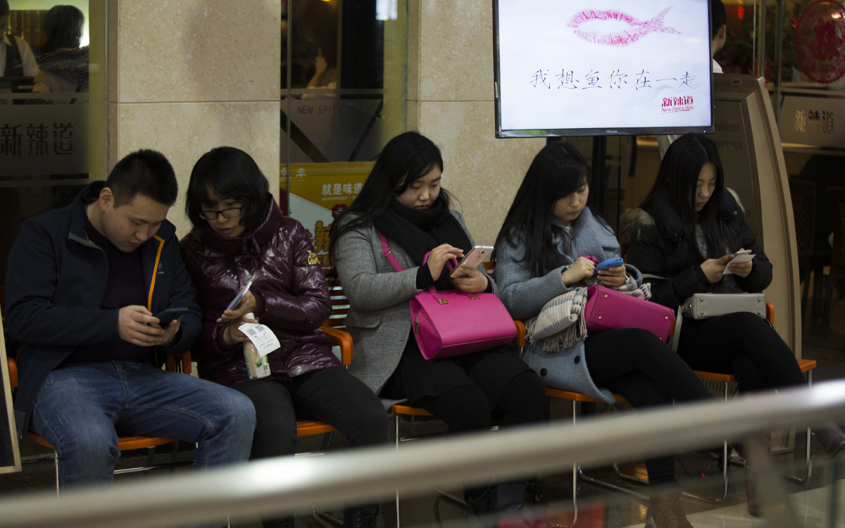 一餐厅的等候区,排队的人每个人手上都捧着手机.