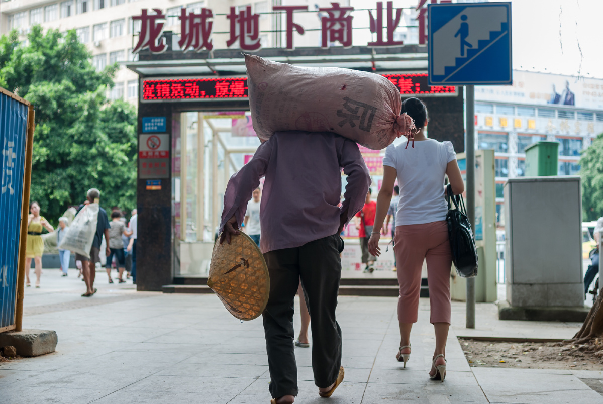 2012年8月12日,柳州,肩扛蛇皮袋的男子为过地下通道做准备.