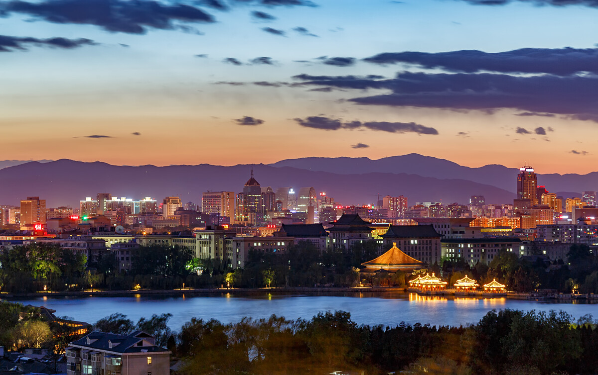 夜幕下的北海公园，从景山上望去，亮灯的古亭与背后繁华都市，交相辉映，绚丽多彩。