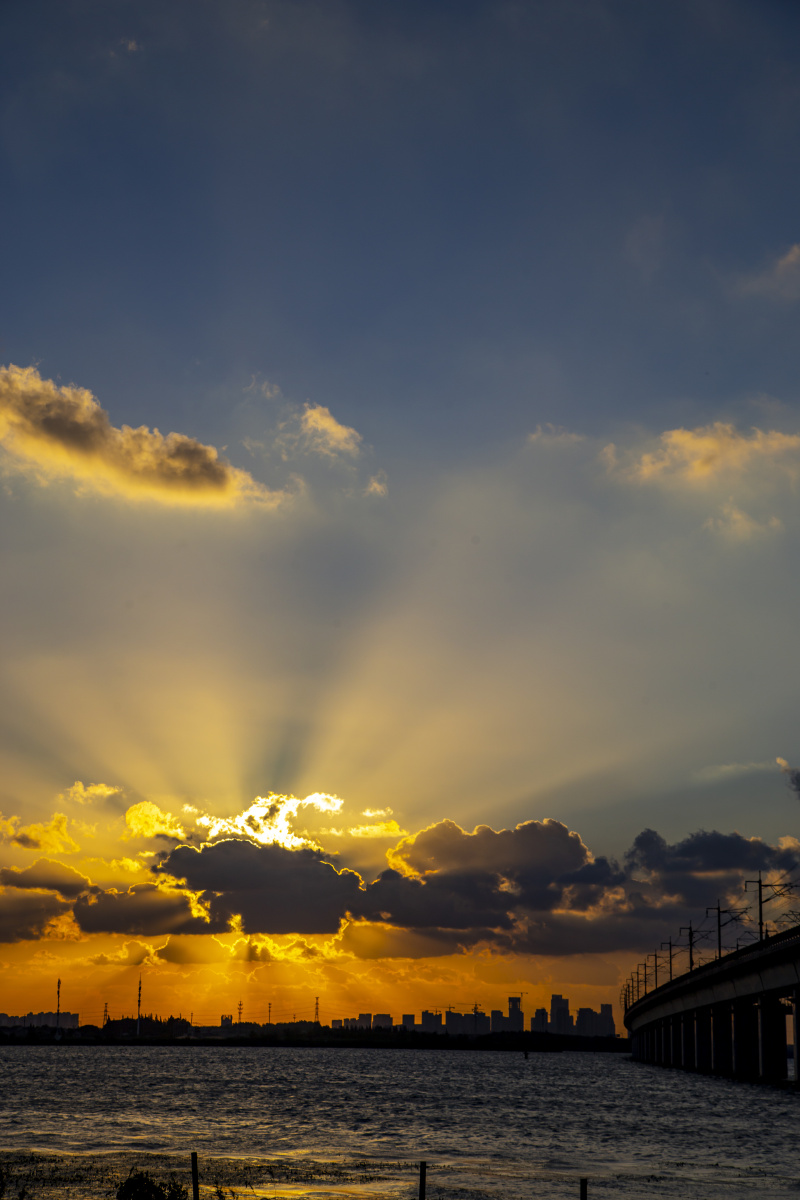 夕阳透过云朵,光芒万丈,照亮了不平静的湖面,美不胜收!