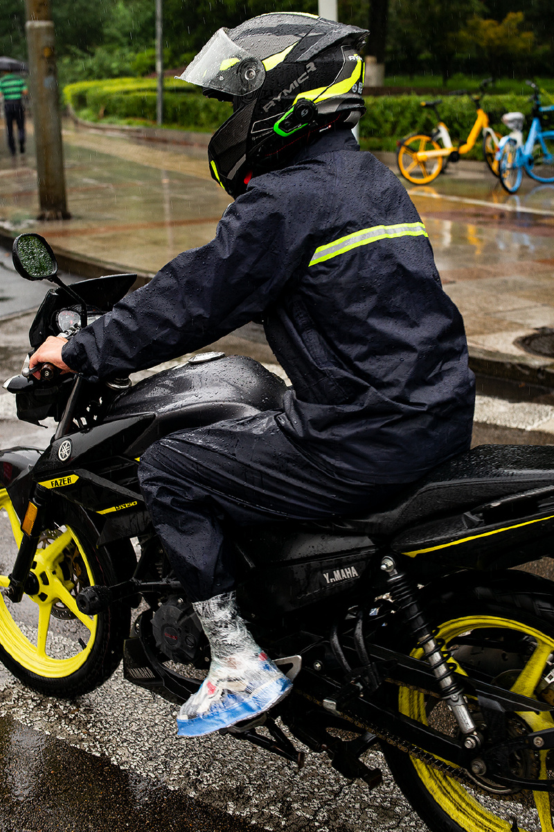 《摩托骑手的自制防雨靴》2021年8月20日,济南,雨中一摩托车手,脚蹬