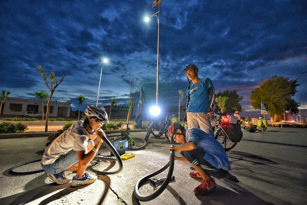 省界处，，宁夏入甘肃，夜幕即将降临，我们加快了踏频，却又爆了路上的第24条胎。大家早已习惯这爆胎日常，两位修理师熟练地拿出工具箱，在日落余晖下天空蓝的可怕，胎爆得也是频繁地可怕。