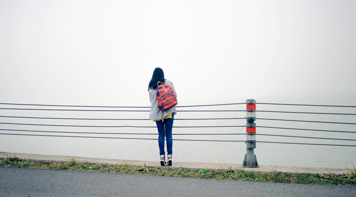 大雨过后,湖面的雾气很深,环湖的盘山公路那边,旅行的姑娘在独自行走.