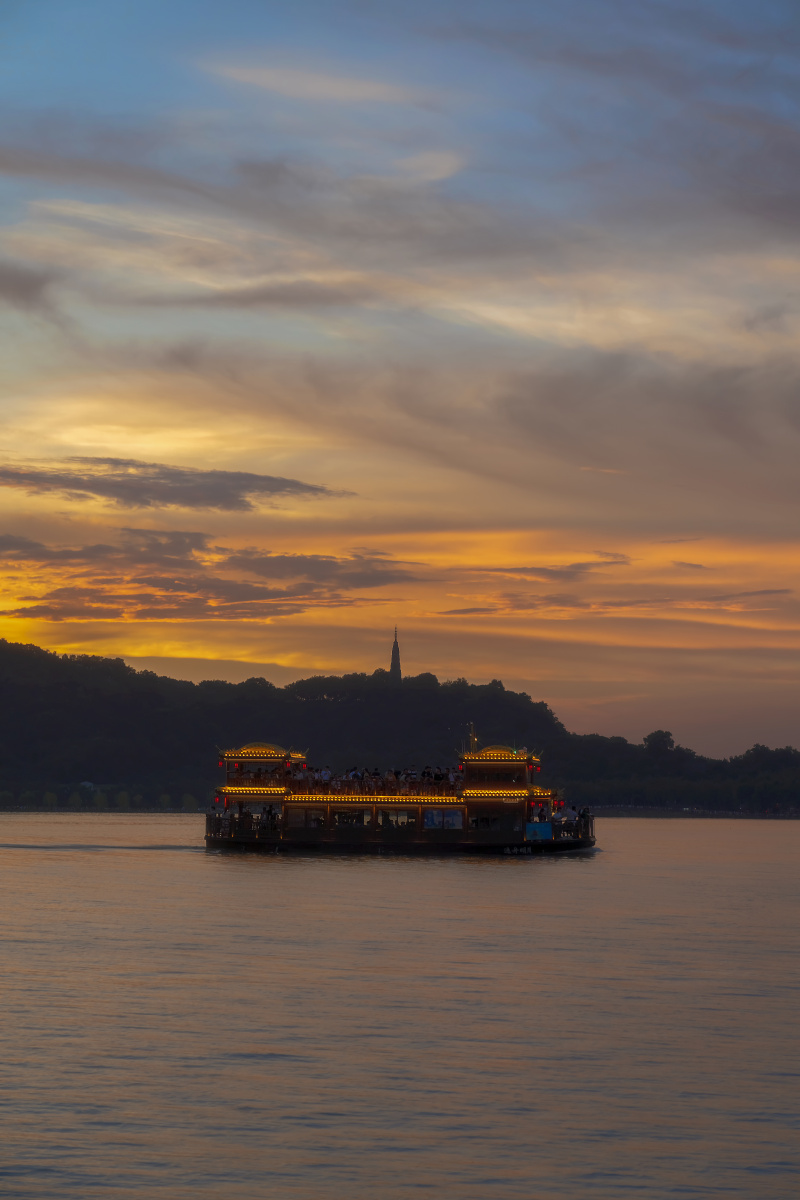 西湖流霞傍晚晚霞映照在西湖上游船和保俶塔披上了金色