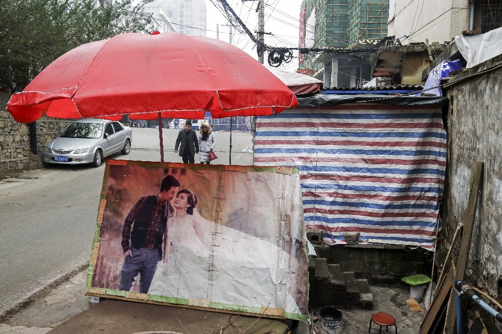街头，被遗弃的结婚照被小摊主用来挡风避雨，照片中的青年男女爱情究竟出现了什么问题，珍贵的结婚照被遗弃，爱情的故事发人深思，让人感叹不已；远处走来的一对青年男女书写的又是另一个爱情故事。爱情永远在路上。