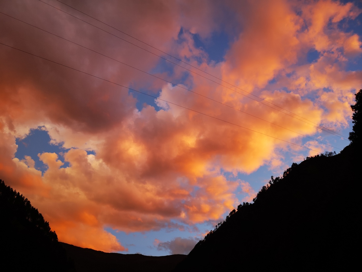 行驶在川西高原的峡谷中,峡谷上空,一边大雨滂沱,一边蓝天红霞