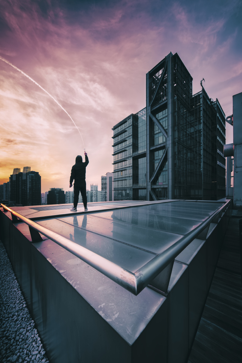 楼顶天台一个人手指指向天空中的飞机
