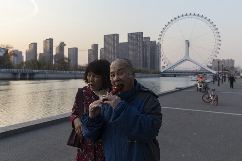 2017年11月,天津,老李和妻子在海河边闲逛,两个人一起分享冰一串糖葫芦。