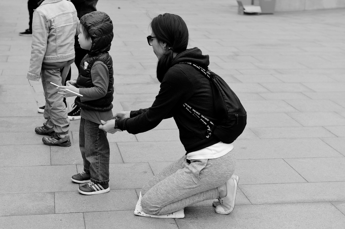 2016年,4月24日,上海街头,一位母亲跪在地上帮孩子整理衣物.