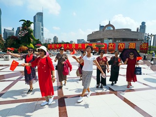 《开心大妈》2019年10月3日人民广场，几位大妈手里拿着小国旗，高兴的边走边唱，“一条大河波浪宽，风吹稻花香两岸.........。是啊，70年走到今天发生了天翻地覆大变化，是应该高兴和高唱。李宝洋 摄13818510917