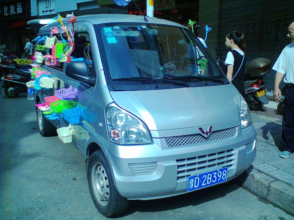 刚刚卸下旅客的面包车，瞬间就披挂上阵，车身上挂满了各种日常生活用品。在这熙来攘往的匆匆社会，人在扮演着不同的角色；物亦变换着不同的角色。