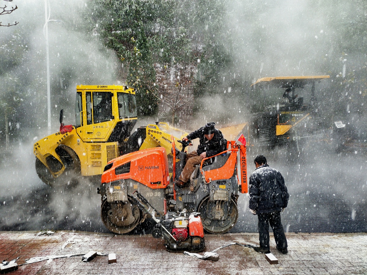 马路工地上修路工在雪中作业中