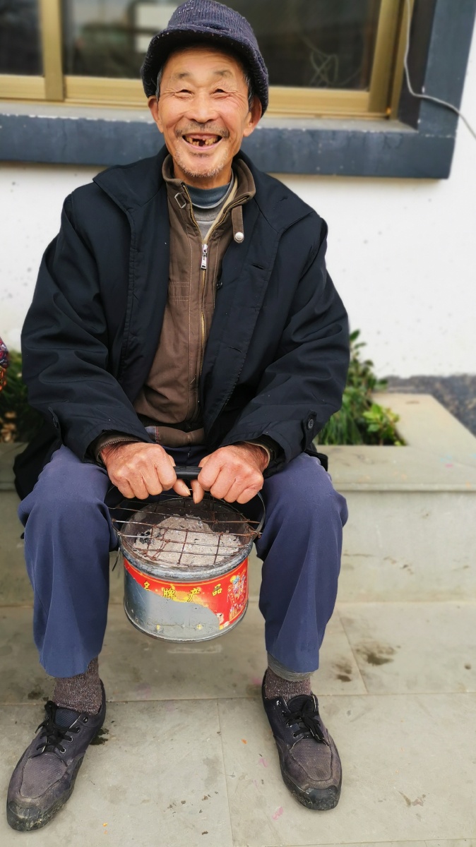 标题老年伴说明冬日里小山村里的老人们都在一起晒太阳聊天开心的过着