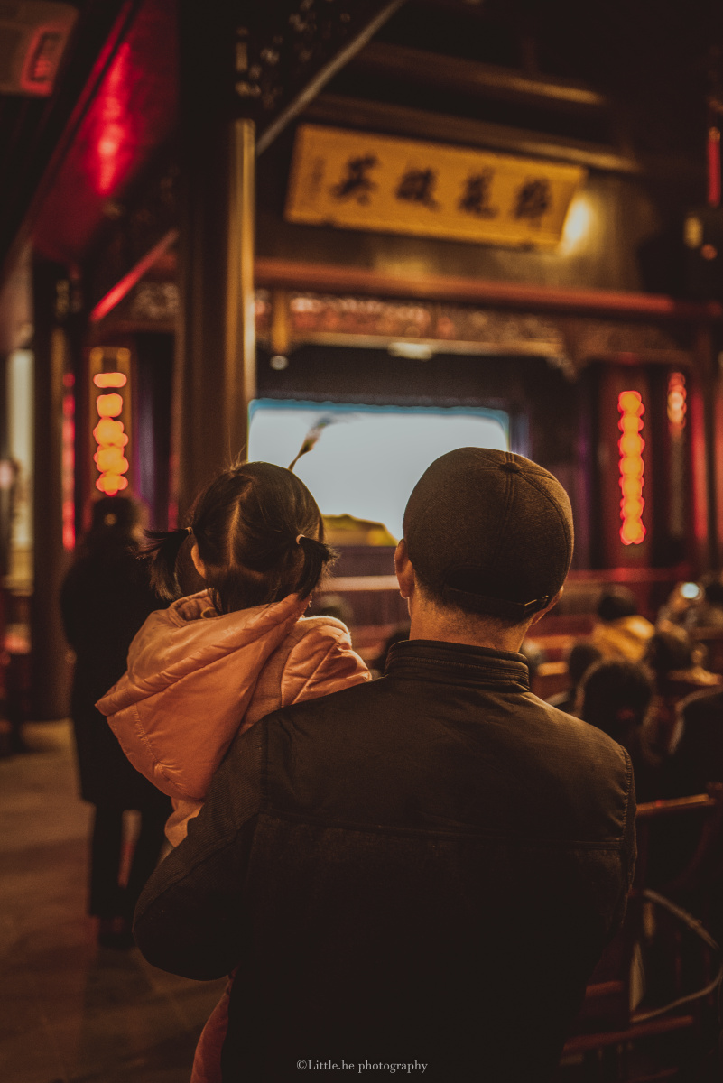 皮影戏老少皆宜,爷爷抱着孙女全神贯注看戏.