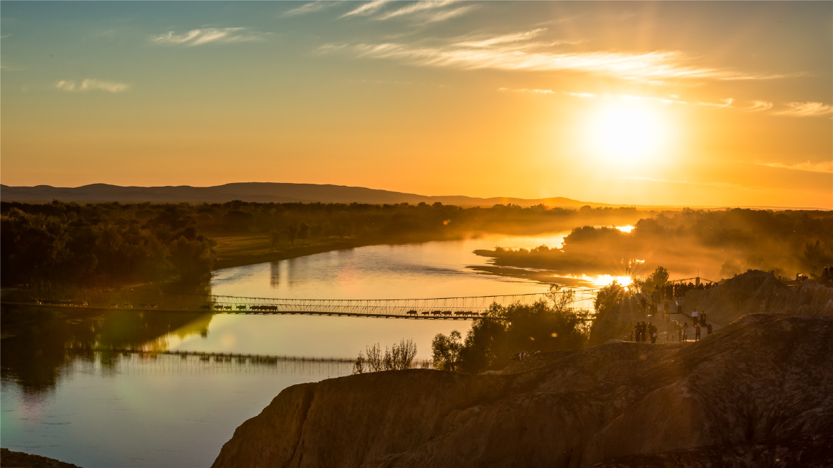 落日下,牧归的牛羊在桥上走过.