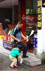《捡起垃圾》：湖南凤凰古城，在爸爸的引导下，孩子将地上的空塑料瓶捡起，准备扔到垃圾箱中。