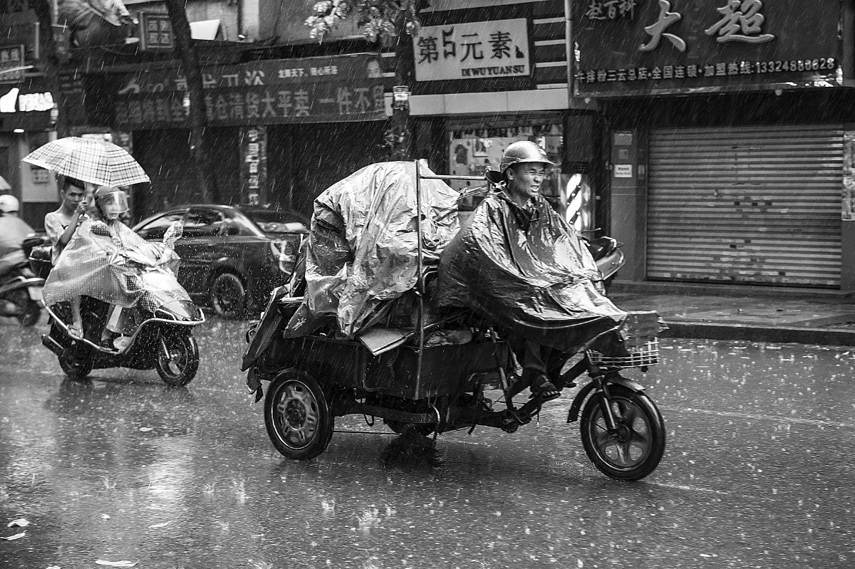 天突然间下大雨,骑三轮车的司机,好不狼狈.
