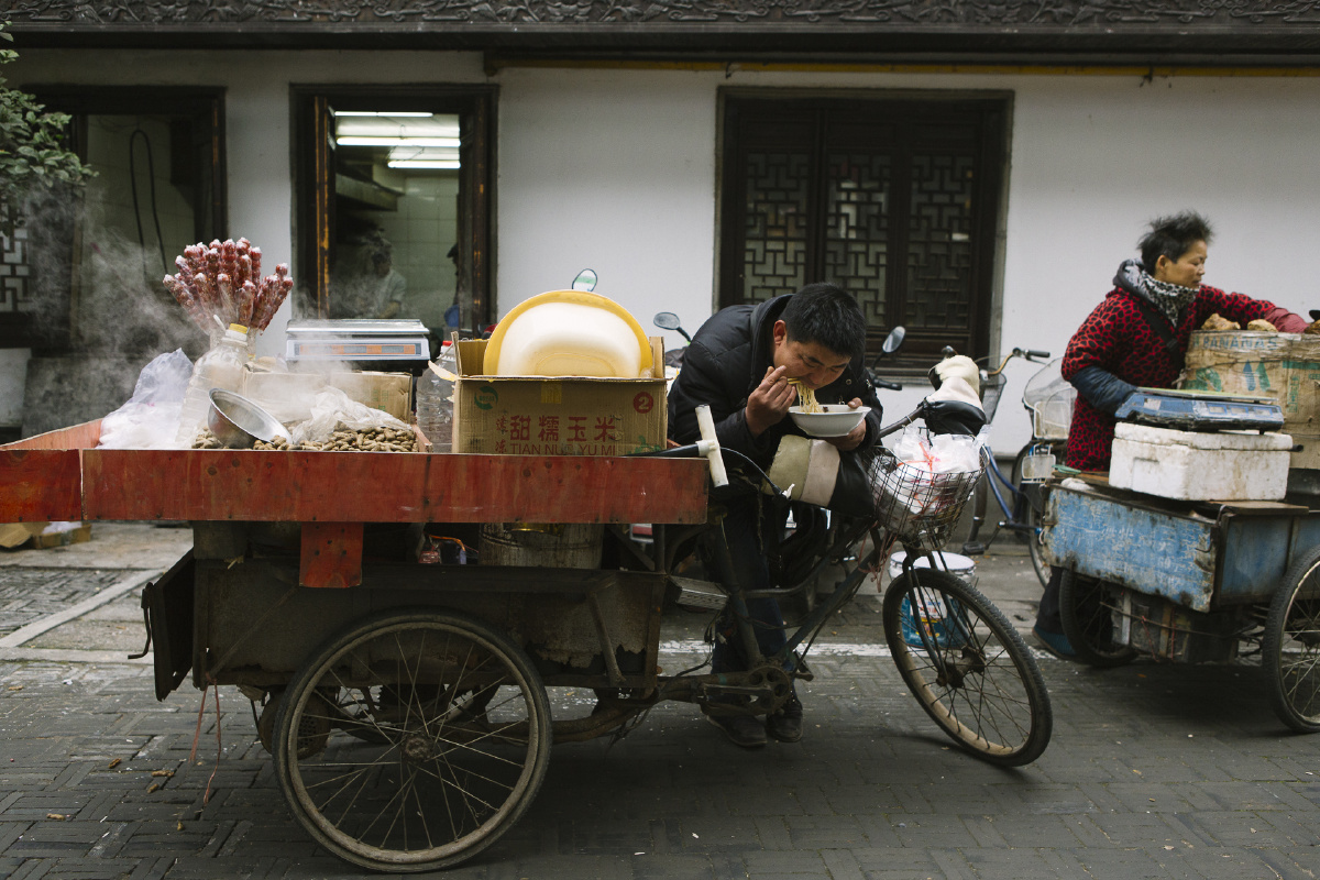 南翔古镇的闹市区里,一辆三轮黄鱼车就是卖糖葫芦盒花生的老板的一亩