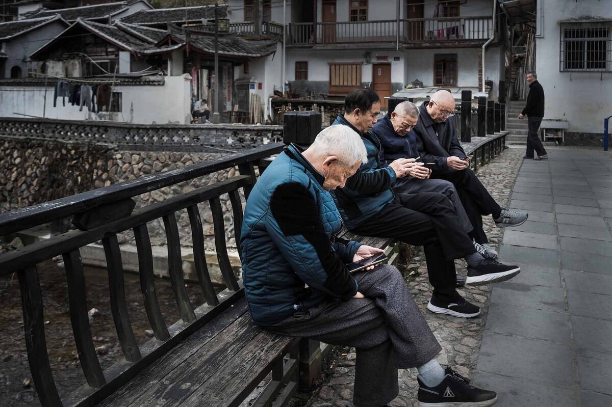 手机的魅力在去新罗万安拍风鸭时村里四个老人坐在桥上都在专注看手机