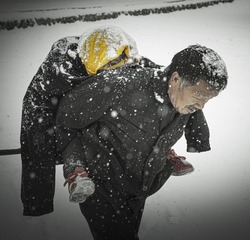 天空突降暴雪，老人将自己的棉服穿着孙女身上，背着她走在放学路上。