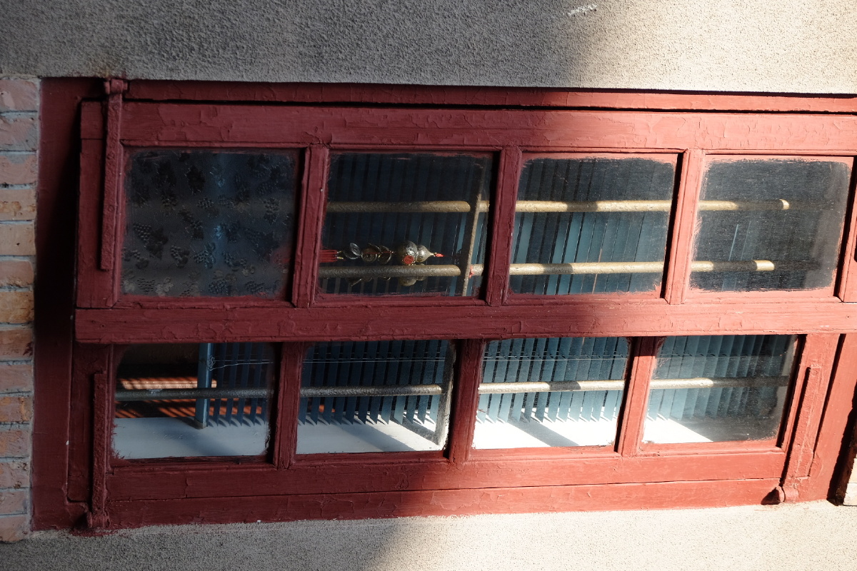 旧建筑的窗户内住户挂着寓意平安健康的葫芦在阳光下若隐若现