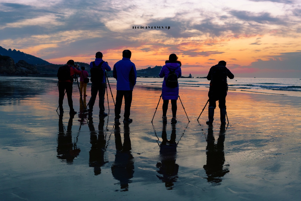 摄影师们在退潮的海滩期待日出