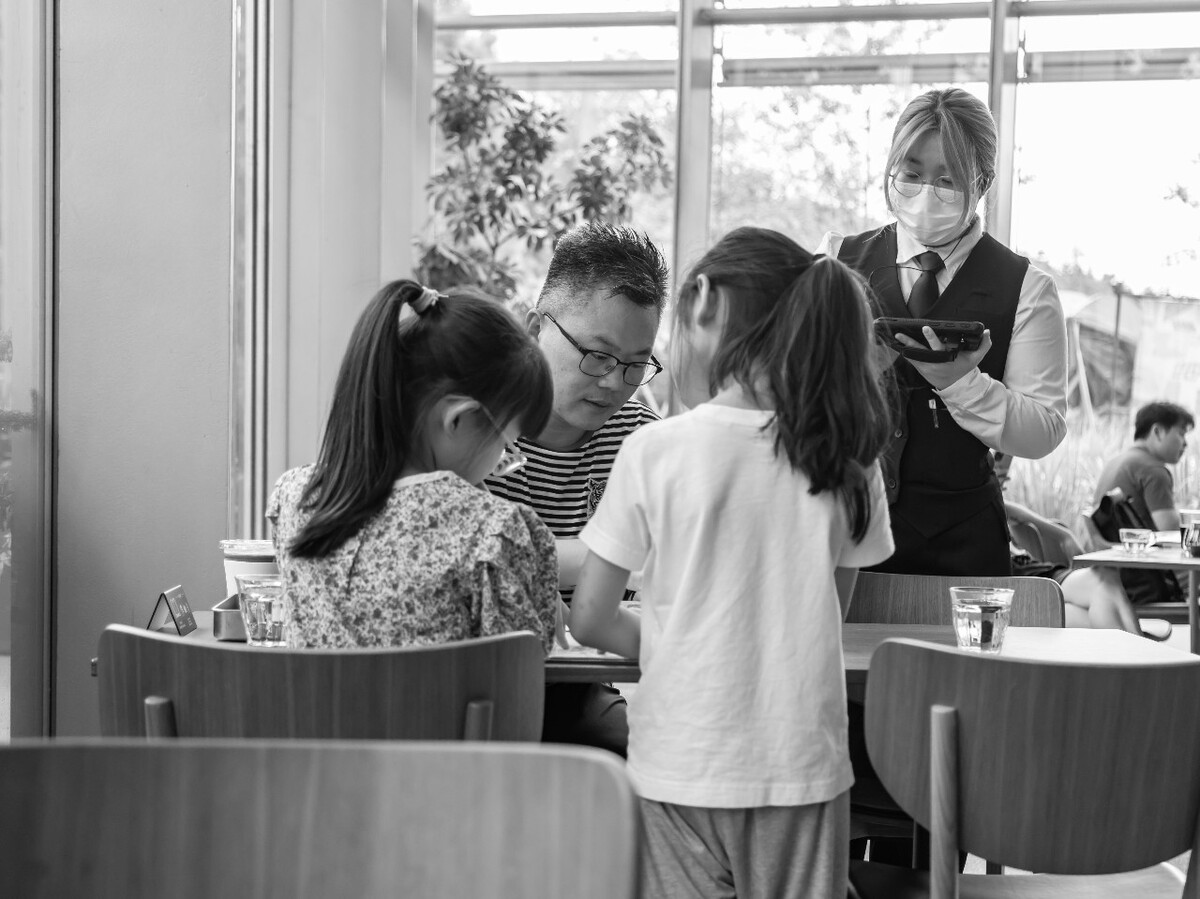 2021.06.26 杭州 鸢尾书店拍摄。吃饭的时候父亲给两个女儿讲吃饭礼仪,吃饭少说话,还给女儿们讲咖啡和红茶的区别还让两个女儿给自己打分,是一般啊,还是还不错啊。两个女儿还和上餐的服务员说谢谢。父亲还给两个女儿拍照,两个女儿都摆出了耶的手势。<br />