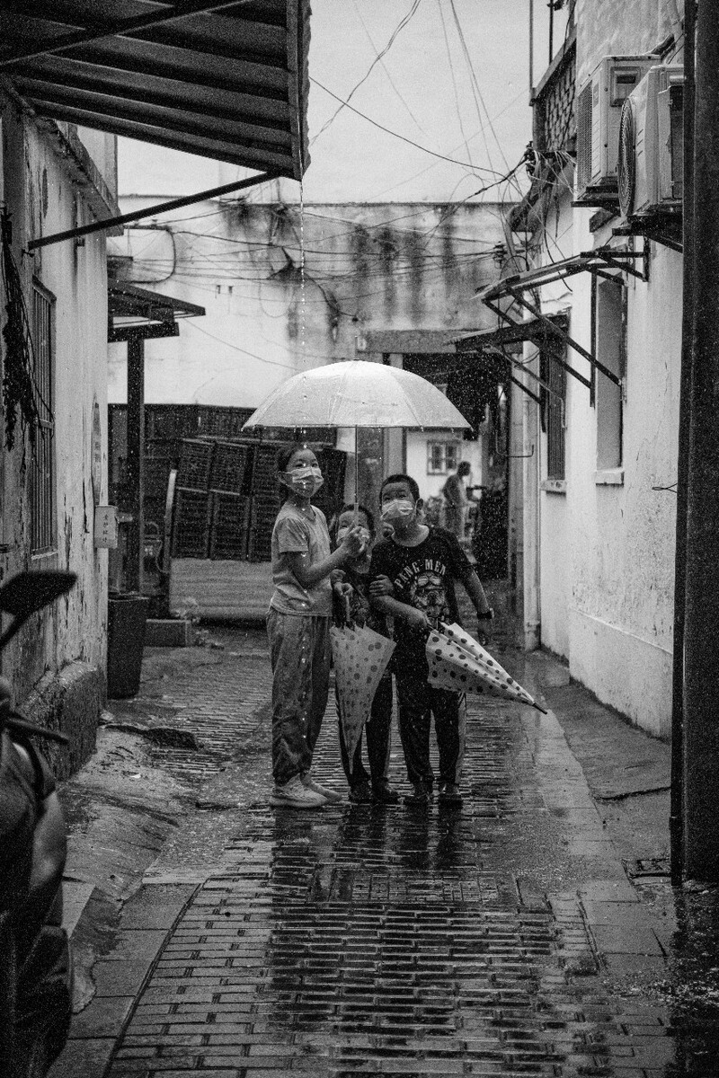 2021.08.13 苏州 山塘街所摄。三个和雨水陪伴着一起玩耍的小朋友,盯着屋檐棚顶留下的雨水。
