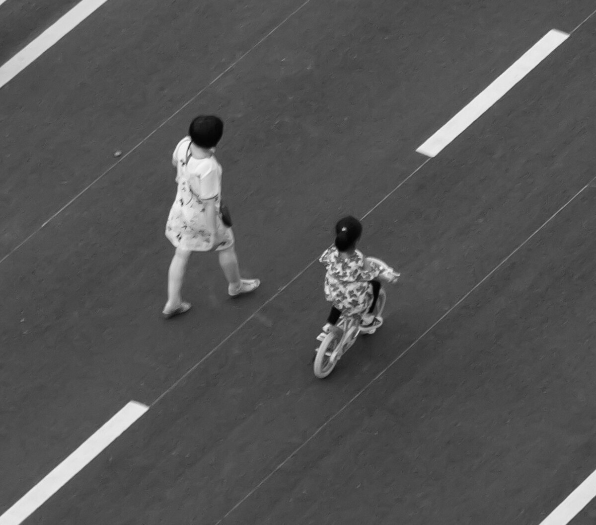 2021.06.23 苏州 吴中区仁泰花园家中拍摄楼下街道。空旷的街道上母亲跟着骑着自行车的女儿。