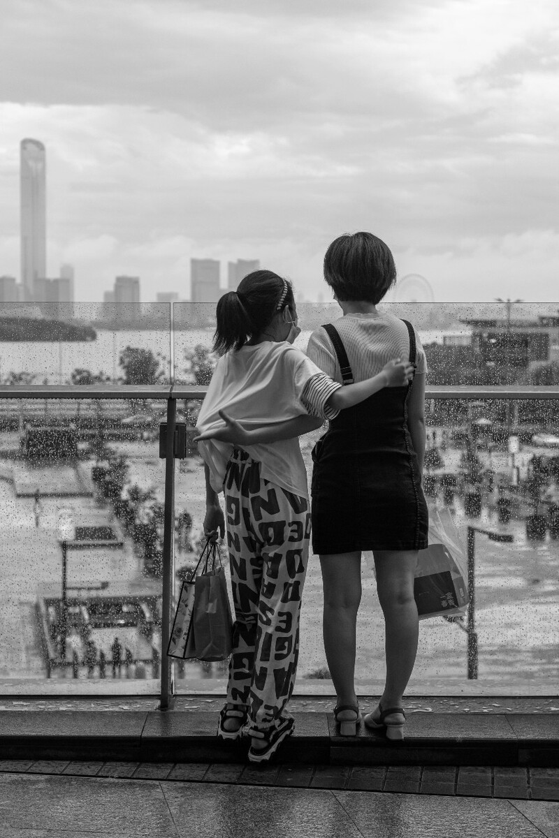 2021.07.08 苏州 苏州中心商场拍摄。母女二人抱着看着外边的雨。