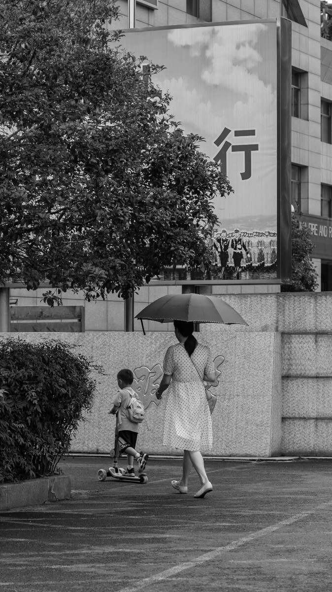 2021.06.26 杭州 机场路拍摄。 儿子骑车在前面,母亲在后面跟着,最后母子俩一起走进了菜场。