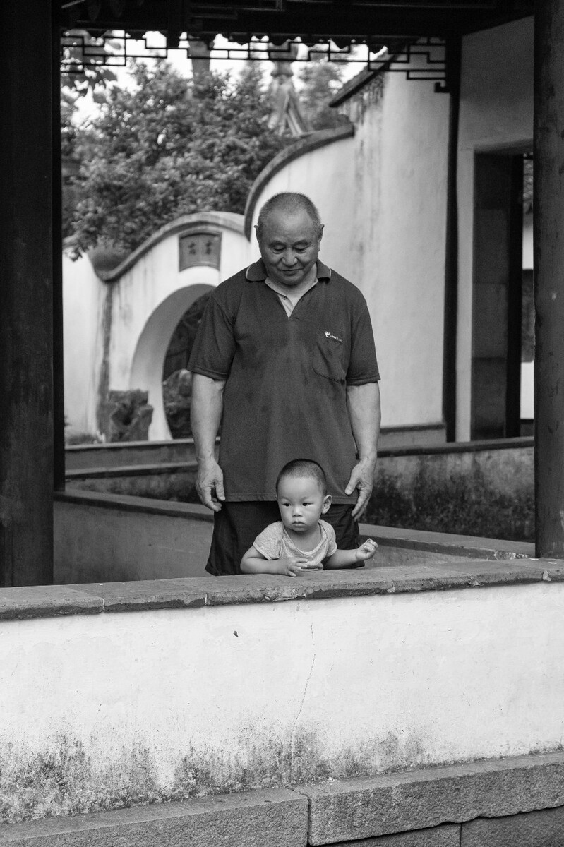 2021.07.05 苏州 怡园拍摄。爷爷跟在孙子身后在怡园里行走,爷爷紧紧跟着,小心翼翼生怕孙子摔倒。