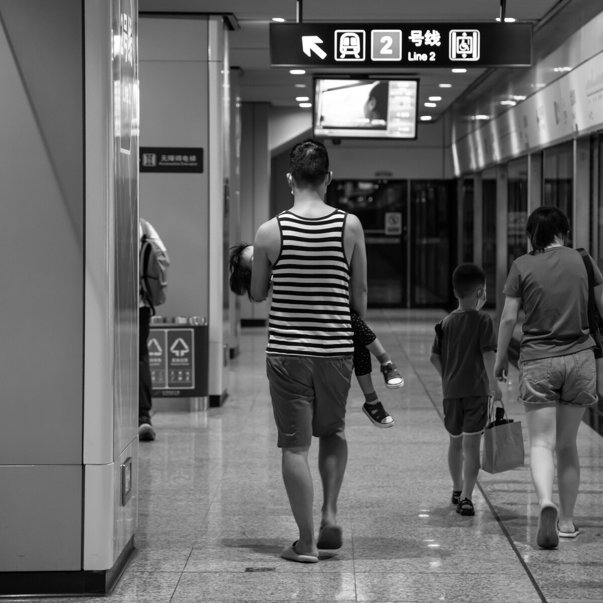 2021.08.13 苏州 盘蠡路地铁站内所摄。七夕当天,在地铁站里看到一家人,妻子和儿子走在右边,老公(父亲)抱着孩子。