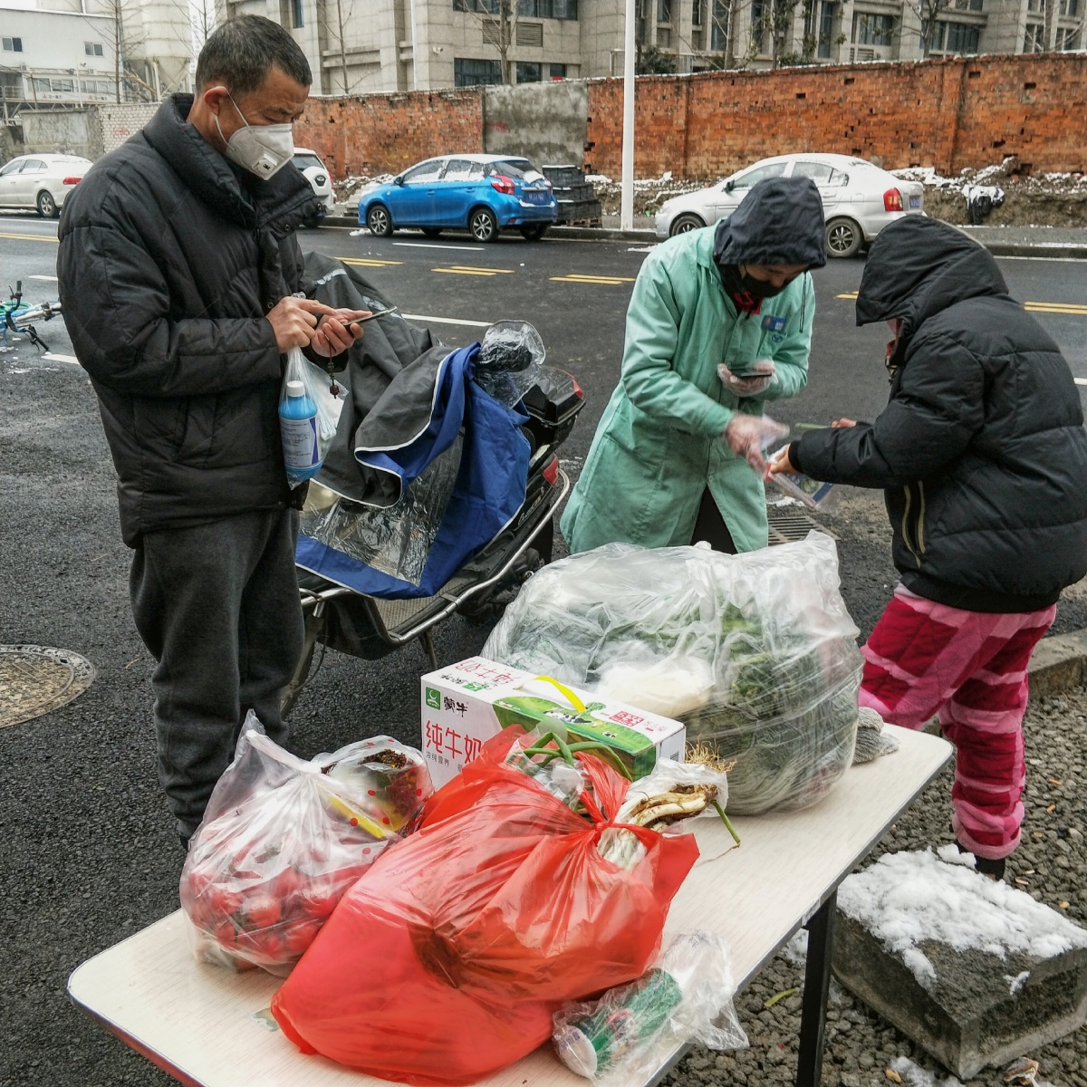 门外，小区住户带着口罩、穿着睡衣，与指定送药人员扫码付款。