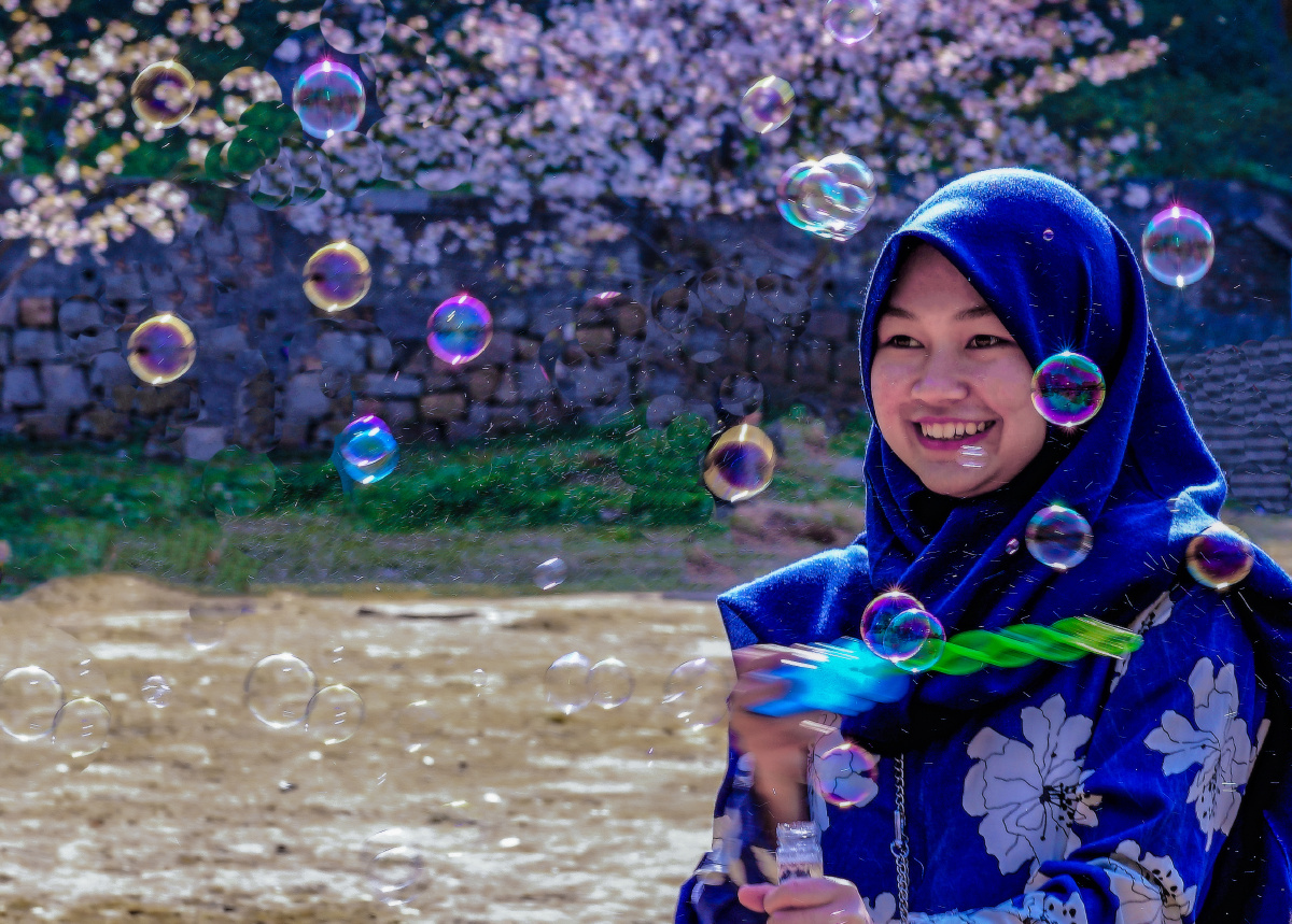 泡泡樱花季节一个南亚女孩在满园樱花的春色里快乐的吹着泡泡