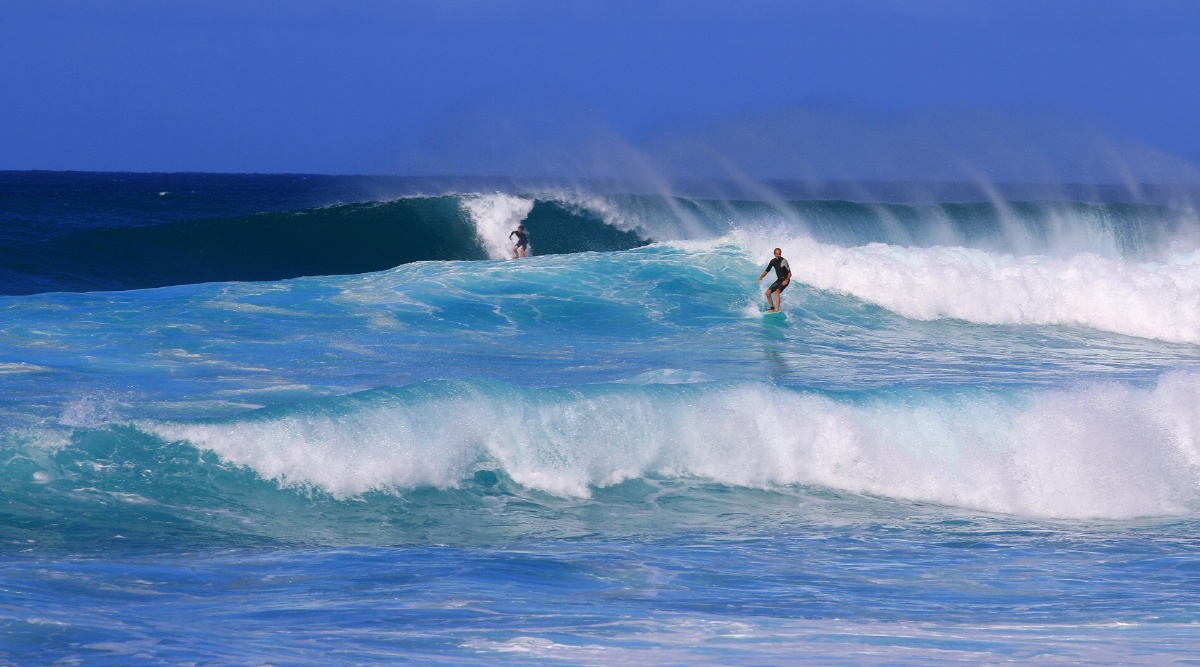 在汹涌的海浪中冲浪少年勇敢的滑行着