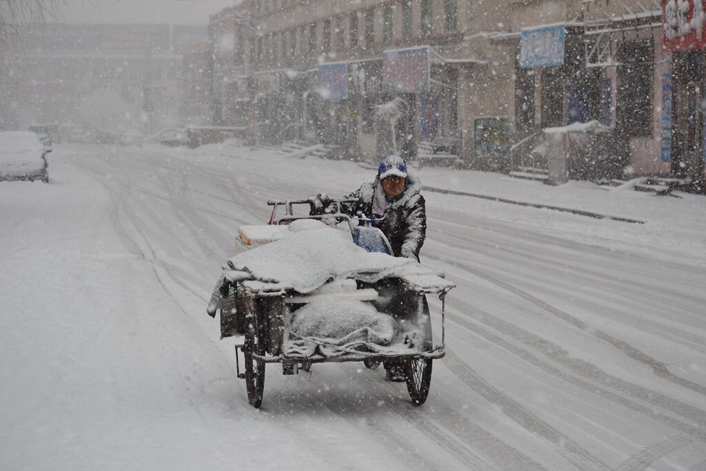 热闹的街路已无一丝灯光，漂落的雪花，艰难的推行着赖以生存的家当，无不表现了百姓的生存的艰辛。昂首向着温暖的家步步行进又给生活带来了希望。