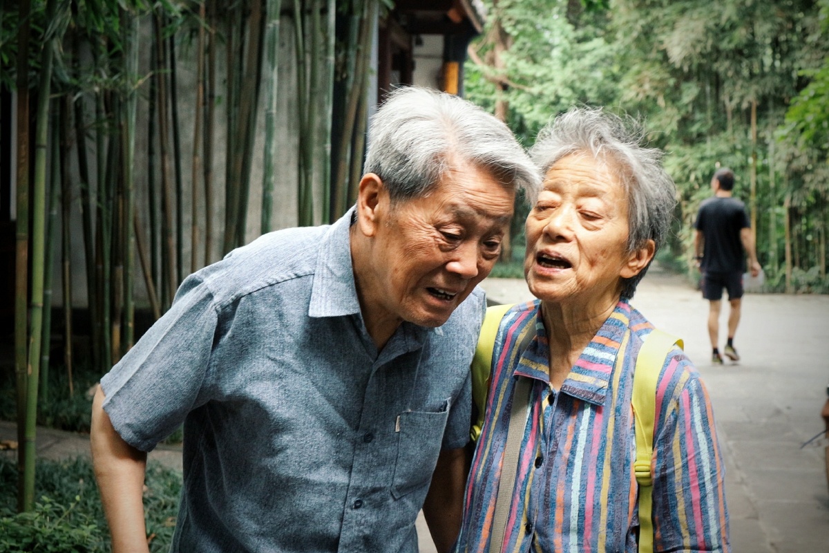 阿婆在对阿公讲话,但是阿公的听力不好,就得凑近低着头听.