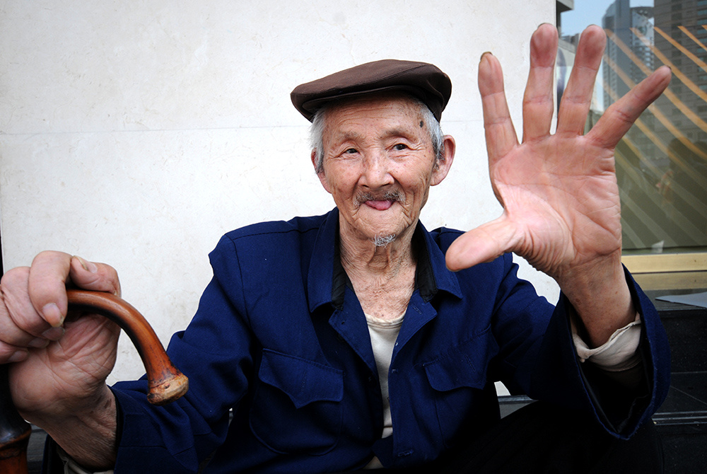 重庆,解放碑步行街头,一位老者用手势给摄影师说;今年我九十五岁了.