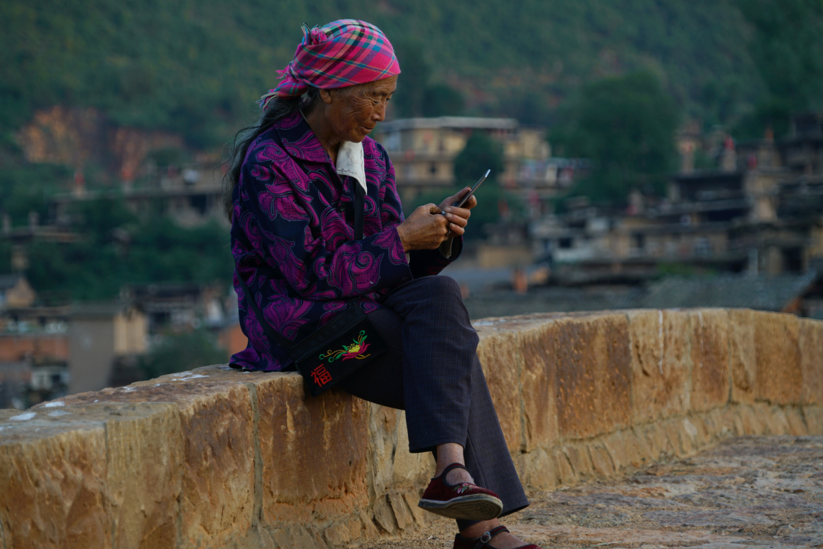 在云南红河泸西县古城子村,一位老妇人手拿手机准备给远方的亲人打