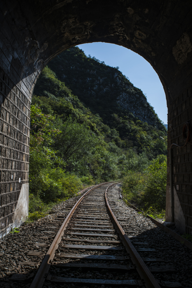 隧道内部向外看穿越群山的铁道铁轨弧形隧道从内向外光影交错京门铁路