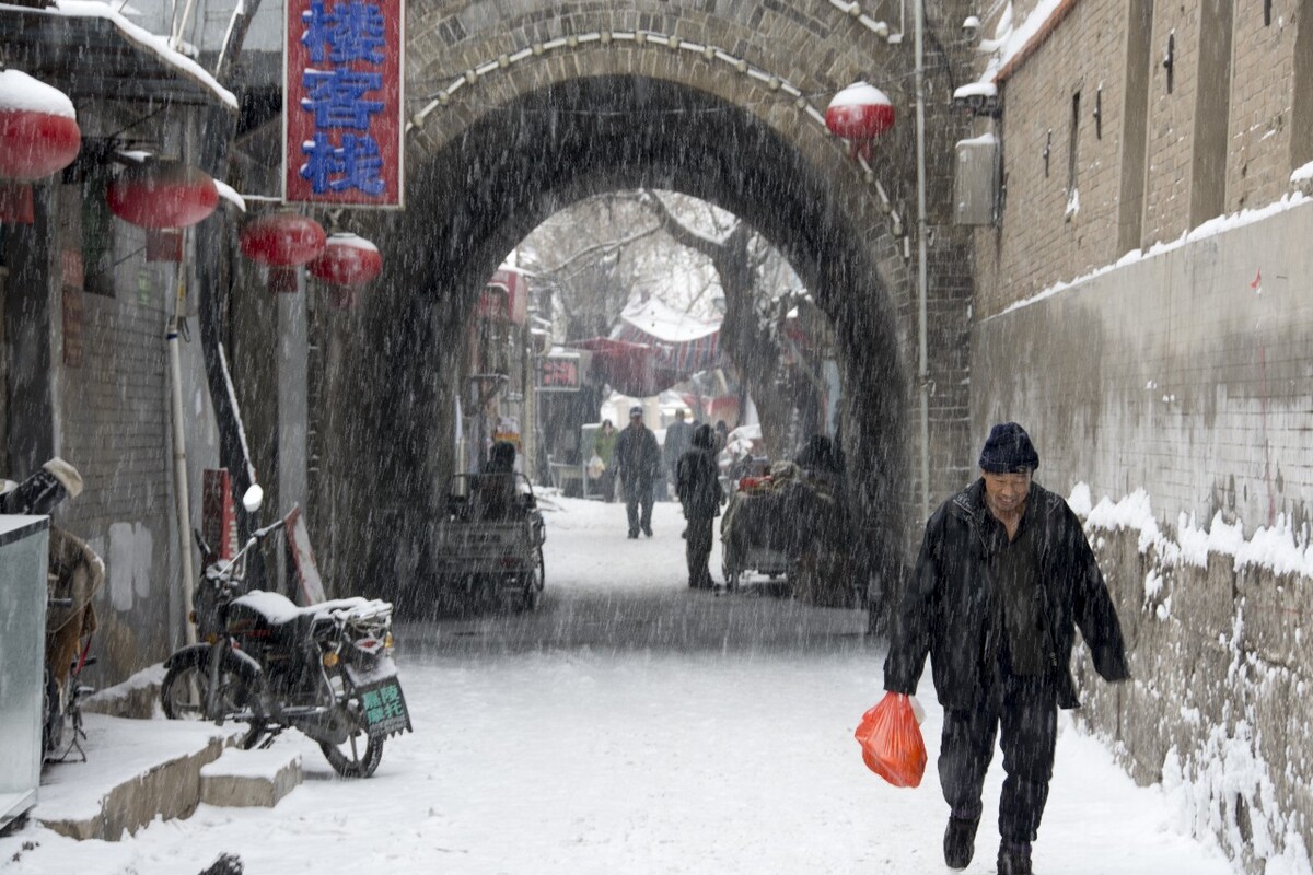 2017年1月7日拍摄于河北省张家口市桥西区堡子里，雪依然在下，一个买菜的男人走了过来。