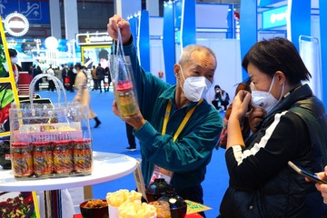 进博会上，澳门展商（左）向观众推介参展的“马拉盏酱”。光明日报记者郭俊锋摄