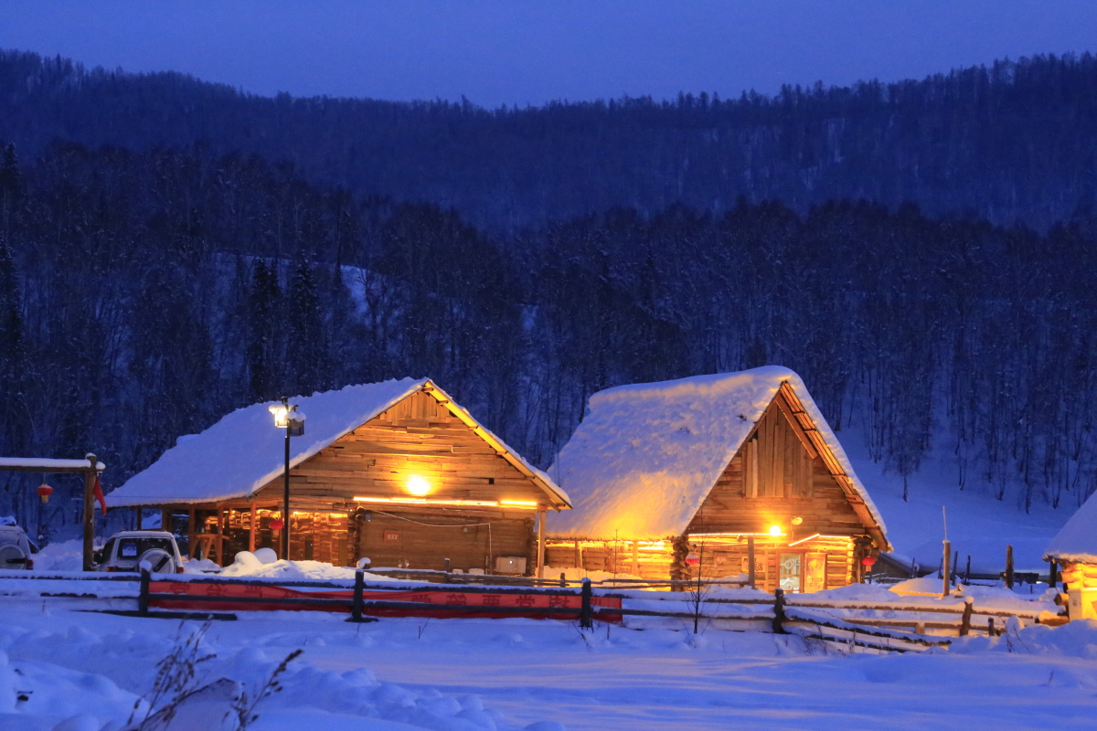 冬日的傍晚温柔的灯光照在禾木村的小屋上显得那样的温馨如久别的家园
