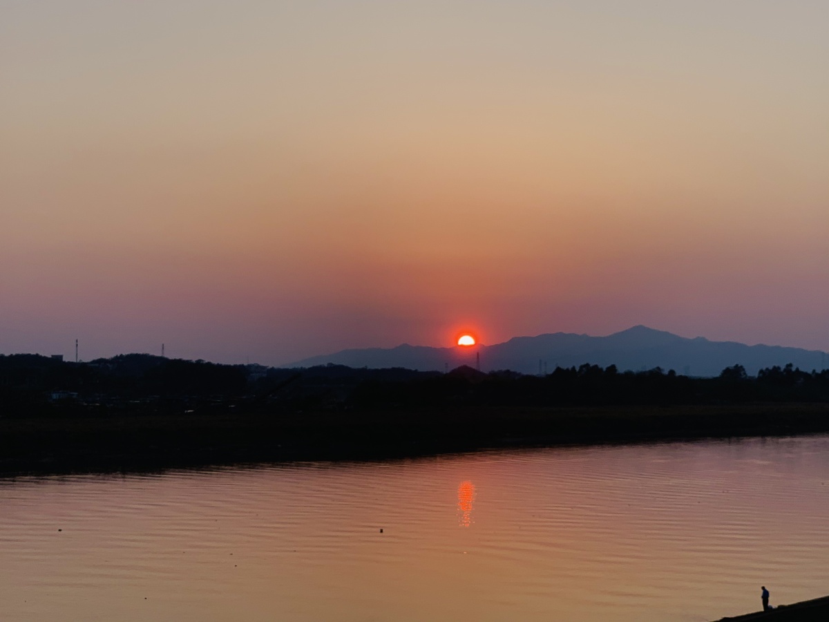 夕阳西下,落日余晖一枚红日落下,落进那远处山峦的阴影里