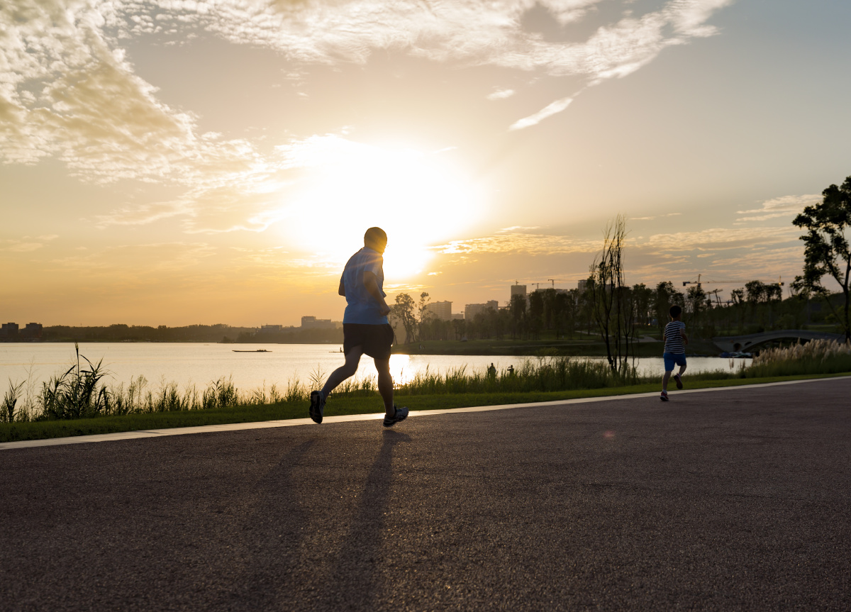在成都兴隆湖畔,日落时分的阳光依然刺眼,一对父子正在湖边跑步锻炼