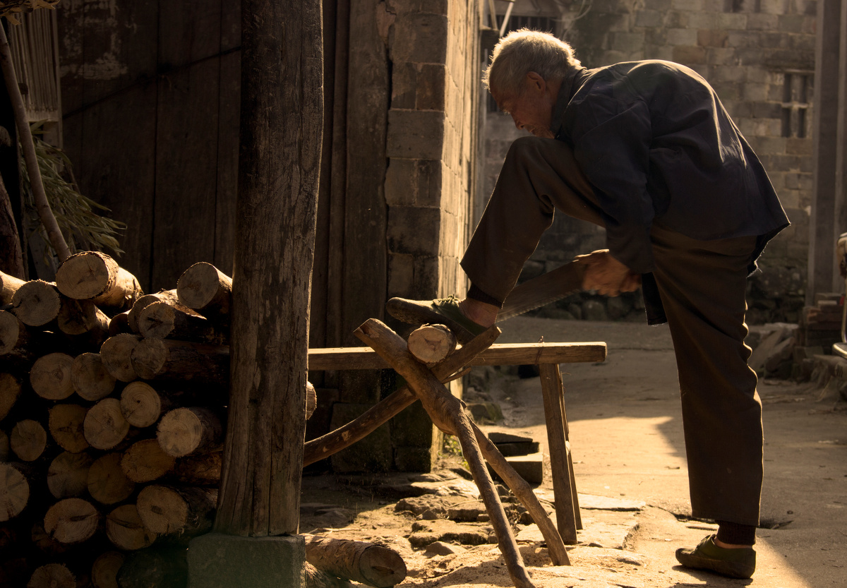 阳光洒在身上的感觉真好,老家的邻居老爷爷在砍柴.