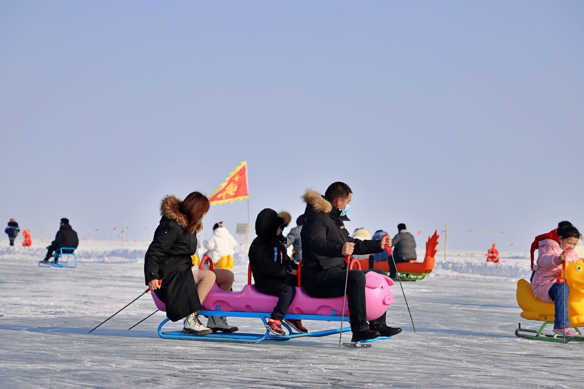2021年12月25日,新疆博湖县大河口景区,游客在玩冰上爬犁.