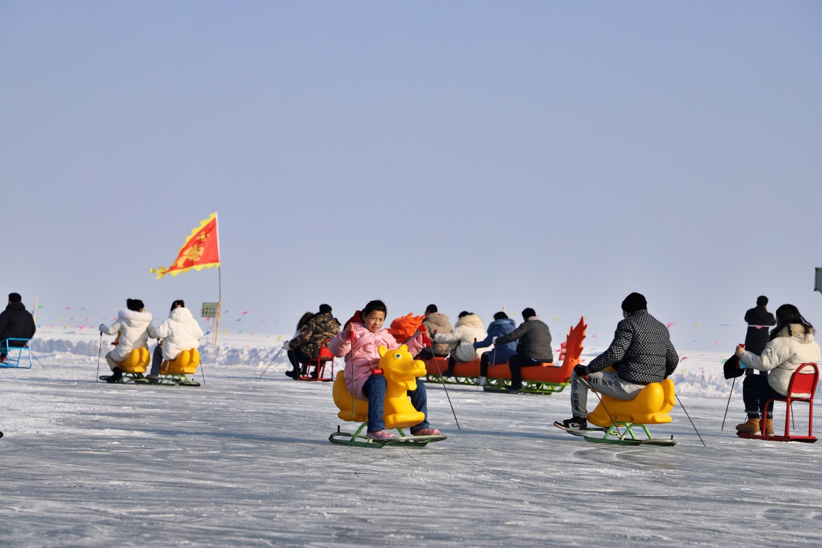2021年12月25日,新疆博湖县大河口景区,游客在玩冰上爬犁.
